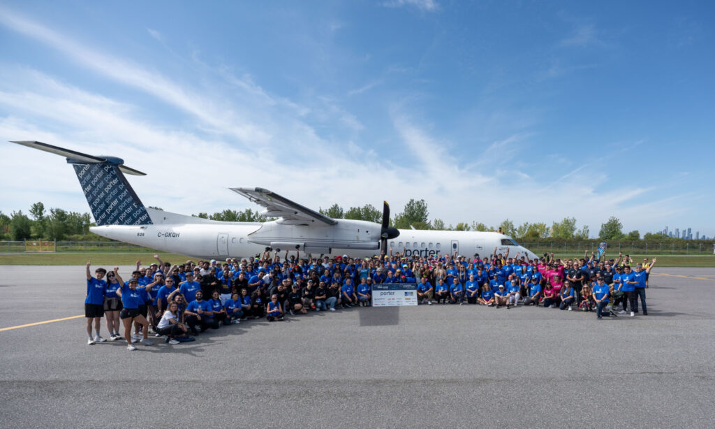 Large gathering on the runway with a Porter plane in the background.
