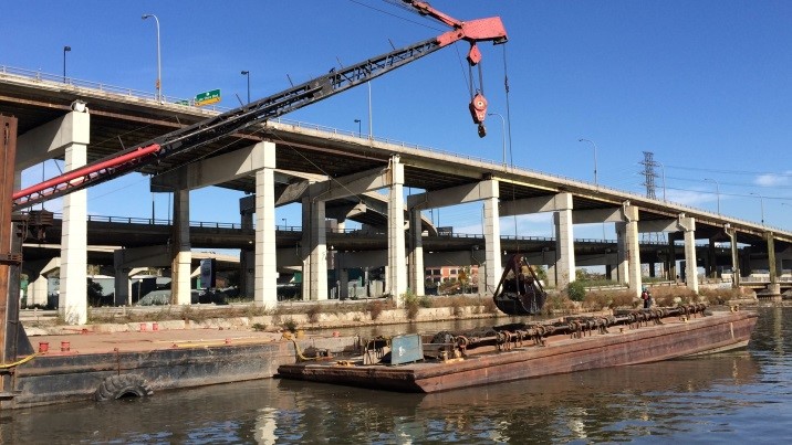 Une benne preneuse montée sur grue drague le chenal Keating.