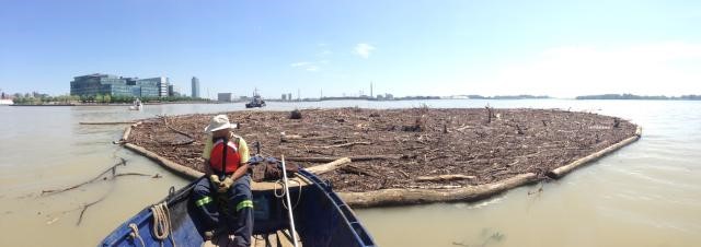 Un membre d’équipage remorque un filet rempli de débris derrière un bateau de travail.