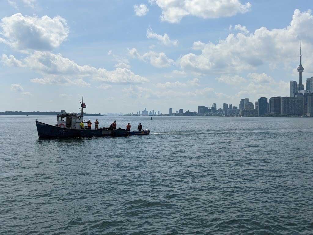Un remorqueur de l’Administration portuaire de Toronto en activité dans le havre, la ville en arrière-plan.