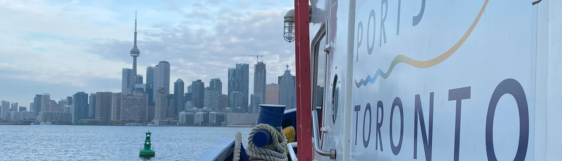 Photo of the the Toronto Port Authority logo on a ship with the Toronto City skyline in the background