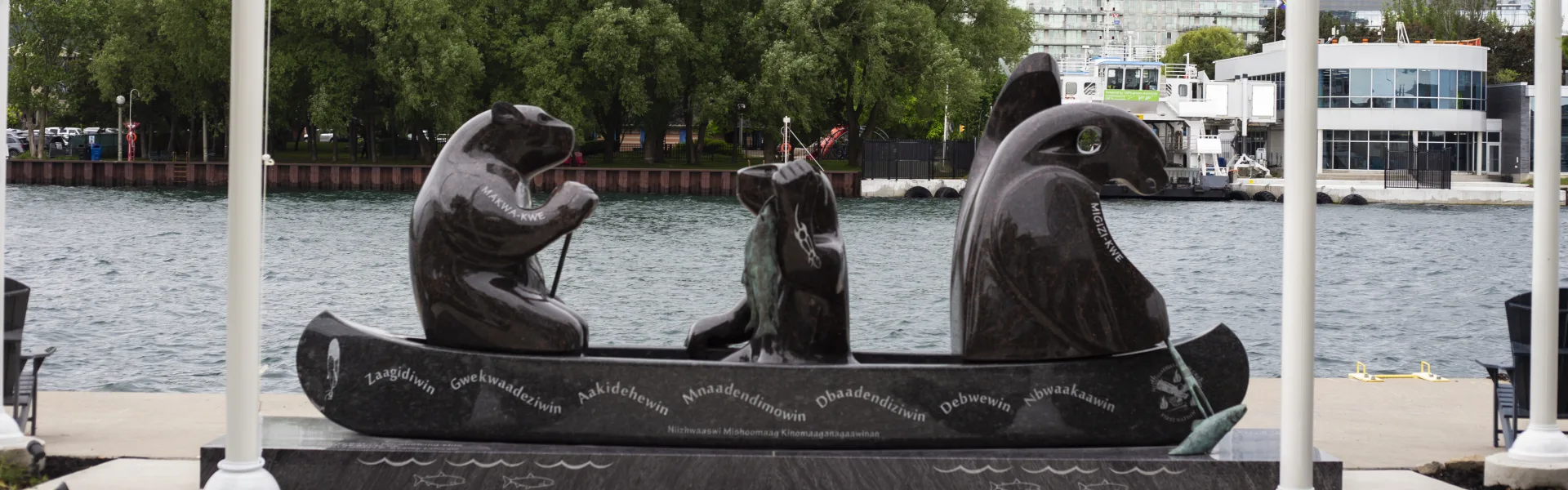 Une sculpture de granit représentant un canot portant un ours, une figure humaine et un aigle sur le secteur riverain de Toronto, gravée des sept enseignements des grands-pères.