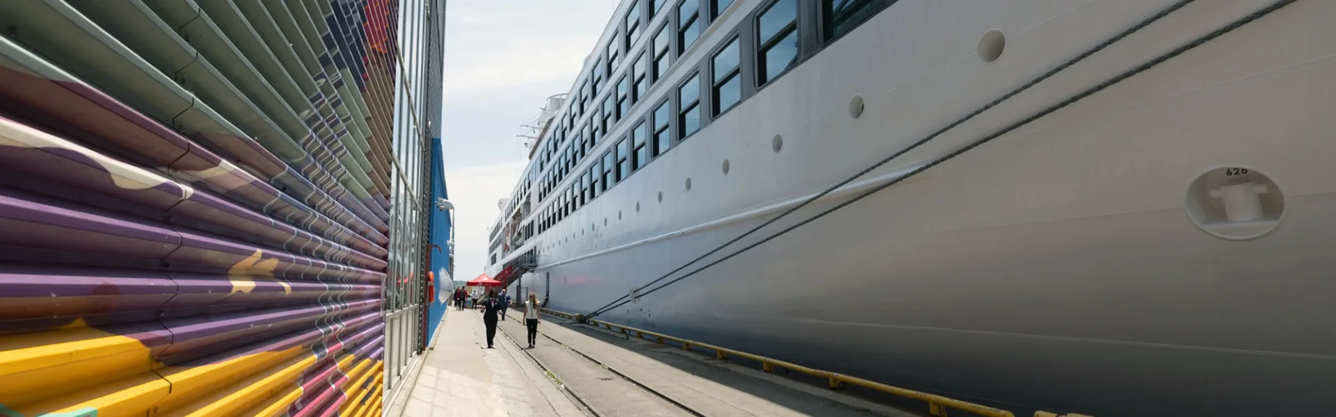Un navire de croisière à quai au Port de Toronto, le long du terminal de croisière orné d’une murale.